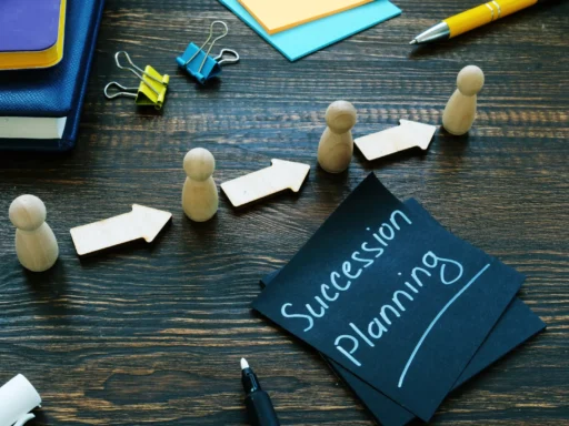 Wooden figures and arrows arranged in a line beside notes labeled “Succession Planning” on a desk.