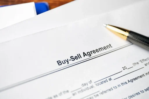 Close-up of a Buy-Sell Agreement document with a pen resting on the page.