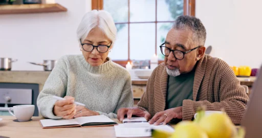 Older couple reviewing financial papers at home while updating their will and estate plan.
