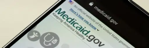 A smartphone screen showing the Medicaid.gov website, including the logo and navigation bar.