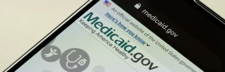 A smartphone screen showing the Medicaid.gov website, including the logo and navigation bar.