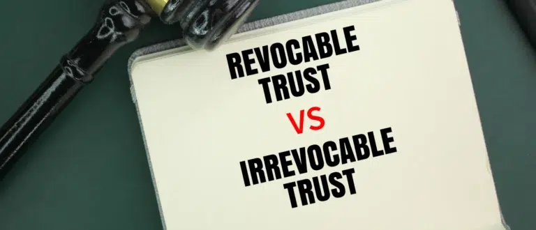 A notebook labeled “Revocable Trust vs Irrevocable Trust” beside a judge’s gavel and black pen on a green desk.